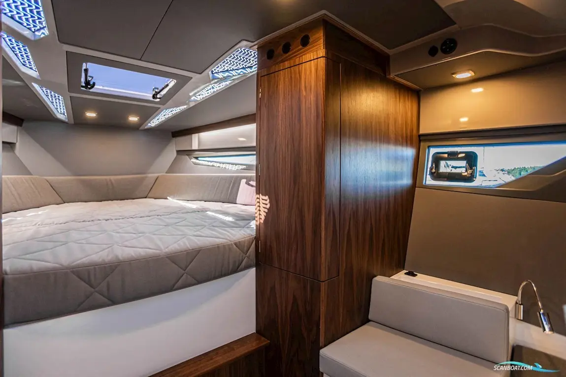 Modern boat interior featuring a large bed, wooden cabinetry, and overhead lights, with a window showing the exterior view.